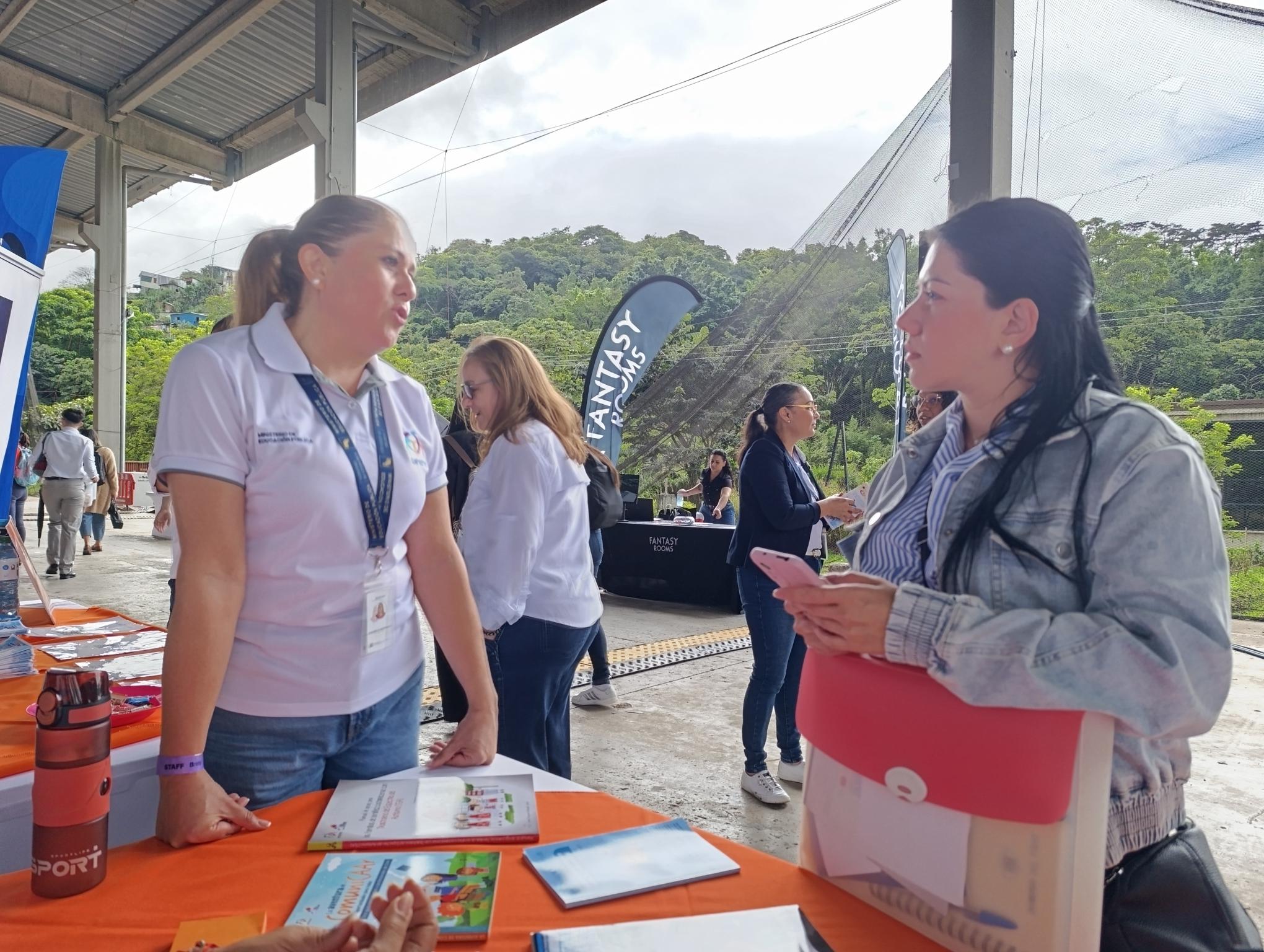 Funcionaria del CENAREC atendiendo a asistente a la feria